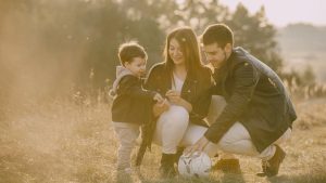 A cheerful family bonding outdoors with a soccer ball, enjoying a sunny day in the grass.